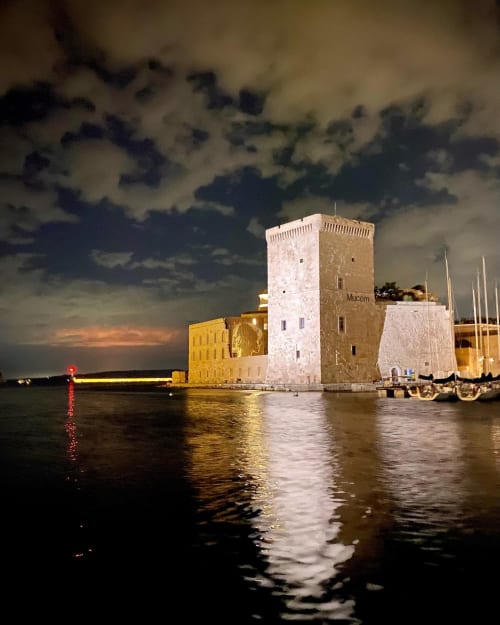 La forteresse historique du port de Marseille illuminée au crépuscule sous un ciel orageux, près de l'hôtel Le Cocon de Chris