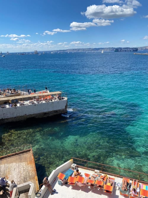 Vue côtière de Marseille avec voiliers, eaux turquoise de la Méditerranée et clients se prélassant à l'hôtel Le Cocon de Chris