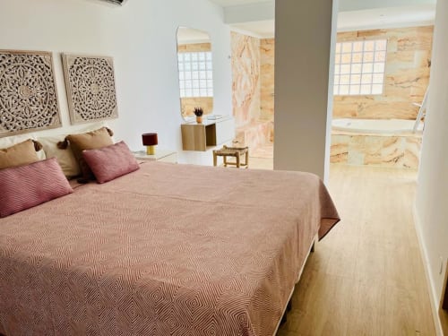 Modern bedroom with geometric patterned bedding, wooden accents, and en-suite bathroom at Sunset ocean view hotel in