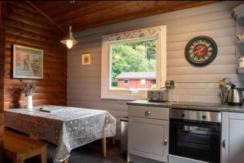 Cozy kitchen cabin interior at Grouse Lodge in Dunoon with wood beams, dining table, and countryside views