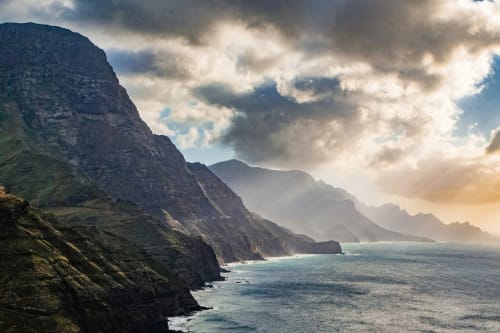 Dramatic coastal cliffs and turquoise ocean waters at Arguineguín, Spain with golden sunset light