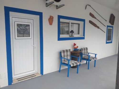 Salão de entrada da Casa do Pão em Campinho com porta de vidro azul, poltronas listradas e decoração rústica