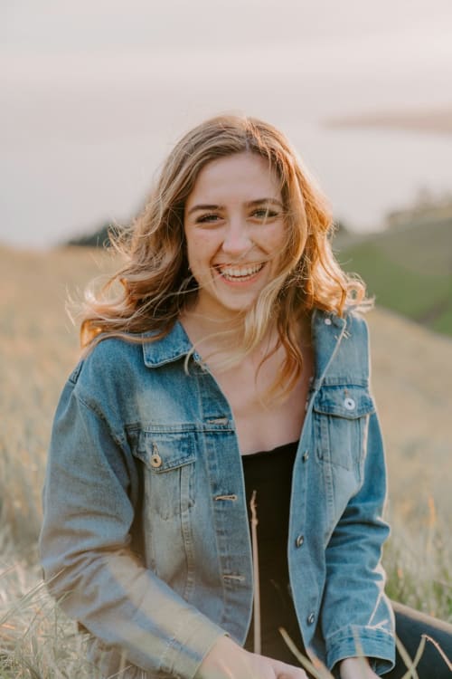 Frau in Jeansjacke lächelnd auf einem ländlichen Feld in der Nähe von Mailand