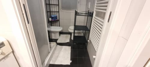 Modernes Badezimmer des Apartments Come a Casa Tua Milano mit schwarzen und weißen Fliesen, Waschbecken, Toilette, Bidet und Handtuchhalter