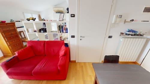 Helles Wohnzimmer mit rotem Ledersofa, Holzböden, weißen Regalen und modernen Annehmlichkeiten in Mailänder Wohnung
