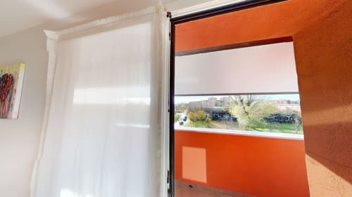 Balkon einer modernen Mailänder Wohnung mit orangefarbener Akzentwand, Stadtblick und zeitgenössischen Fensterbehandlungen