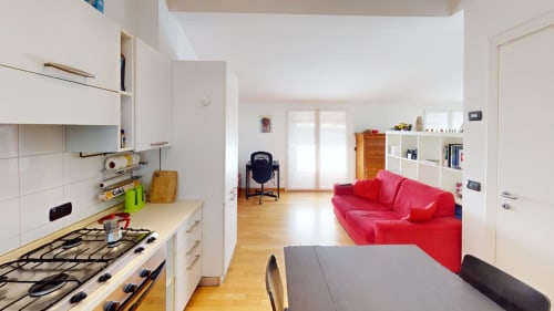 Modernes Mailänder Apartment mit offener Küche, Essbereich und rotem Sofa im Wohnzimmer mit weißen Regalen