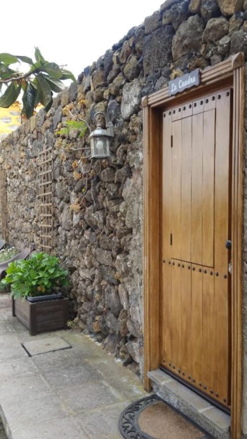 Wooden door entrance to La Cuadra cottage at Casonas de Marengo, Icod de los Vinos, with rustic stone walls and potted plants