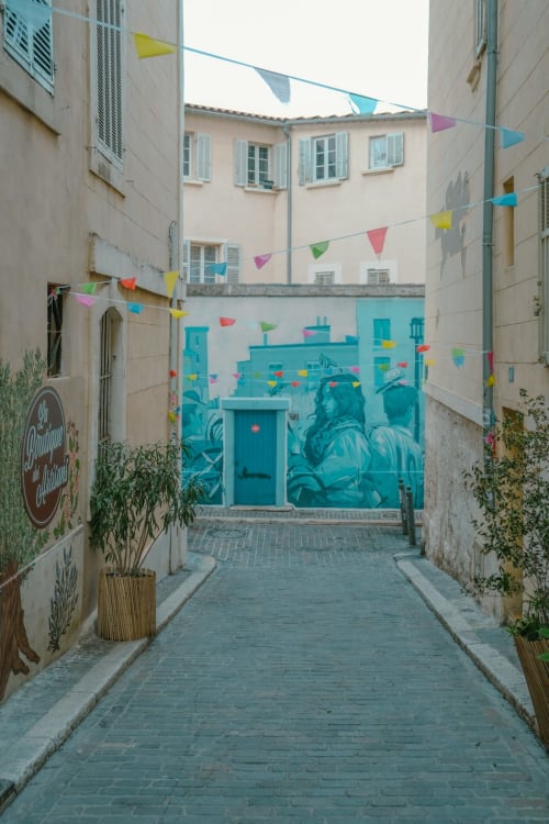Allée colorée de l'hôtel Le Cocon de Chris à Marseille avec fresque turquoise et guirlandes festives