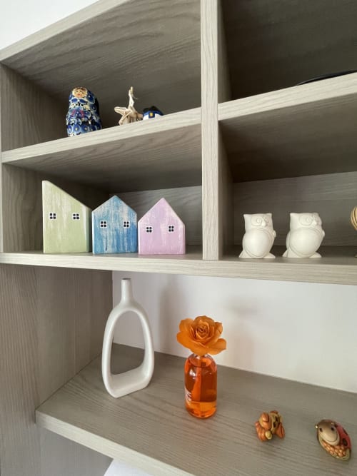 Wooden shelving unit in Varenna by Foot apartment displaying decorative items including miniature houses, owl figurines, and