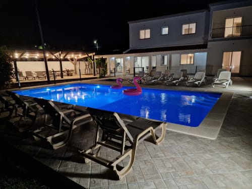 Vue de nuit sur la piscine et la grande terrasse en bois pour les vacanciers venant séjourner dans la villa casaclaudina 1 ou 2