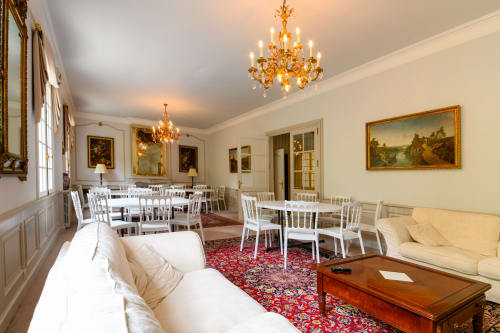 Élégante salle à manger du Domaine de Bize Mirepoix avec lustres en cristal, chaises blanches et décor classique