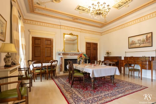 Salle à manger raffinée du Domaine de Bize Manoir à Mirepoix avec lustre en cristal, cheminée et mobilier d'époque.