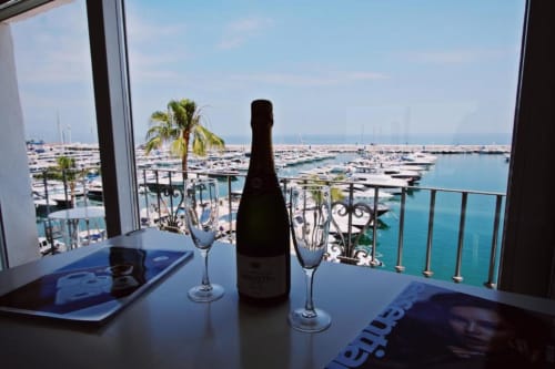 Champagne bottle and glasses on balcony overlooking Puerto Banús marina, Marbella penthouse with sea view