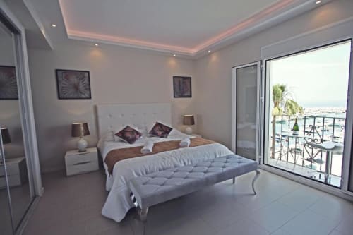 Luxury Marbella penthouse bedroom with sea view balcony, modern furnishings, and Puerto Banús marina view