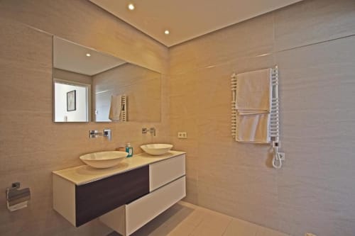Modern luxury bathroom in Marbella penthouse with dual sinks, heated towel rack, and walk-in shower
