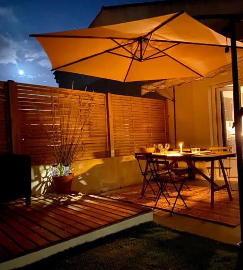 Patio du soir de la villa Tiny Harmony avec parasol orange, table à manger et claustras en bois à Venelles