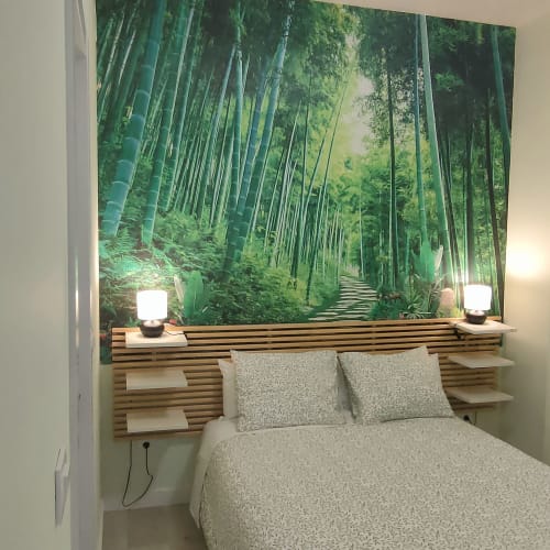 Acogedor dormitorio en apartamento Megaleon de Segovia con mural de bosque de bambú, cabecero de madera e iluminación ambiental