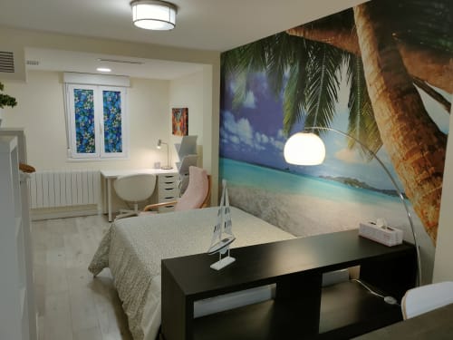 Habitación moderna del hotel Megaleon en Segovia con mural de playa tropical, escritorio de trabajo y mobiliario contemporáneo