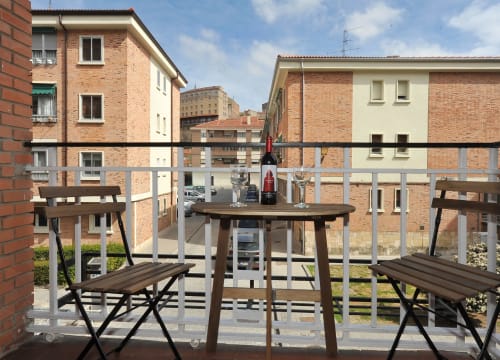 Terraza del hotel Megaleon en Segovia con mesa y bancos de madera con vistas a edificios de ladrillo del patio