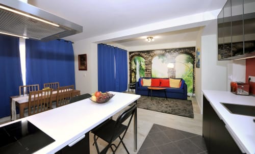 Sala diáfana moderna en Megaleon Segovia con cortinas azules, comedor, cocina y salón con arco de piedra