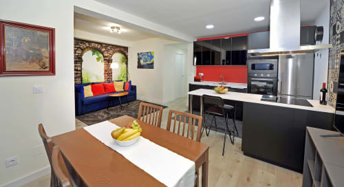 Habitación moderna del hotel Megaleon en Segovia con cocina abierta, zona de comedor con mesa de madera y salón con azulejos