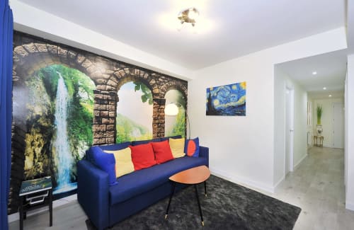 Habitación moderna del hotel Megaleon Segovia con sofá azul, cojines coloridos y mural de arco de piedra