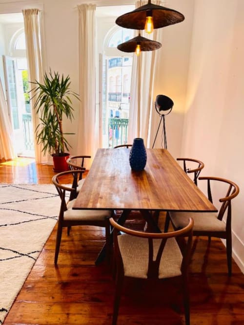 Modern dining area in Lisbon apartment with wooden table, mid-century chairs, pendant lights, and garden view