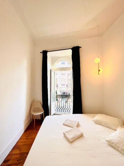 Bright bedroom in Royal Prince Garden Apartments, Lisboa with white bed, black curtains, wooden floor and balcony view