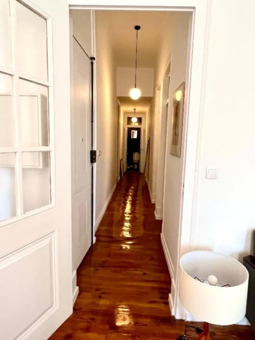 Long hallway with wooden flooring, white doors, pendant lights, and white walls in Royal Prince Garden Apartments, Lisboa