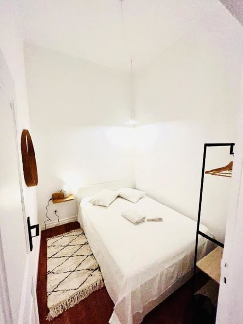 Compact bedroom at Royal Prince Garden Apartments, Lisboa, with white bed, wooden headboard, geometric rug, and garden view