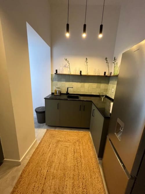 Modern kitchen in Royal Prince Garden Apartments, Lisboa, with dark cabinetry, black countertop, tile backsplash, pendant