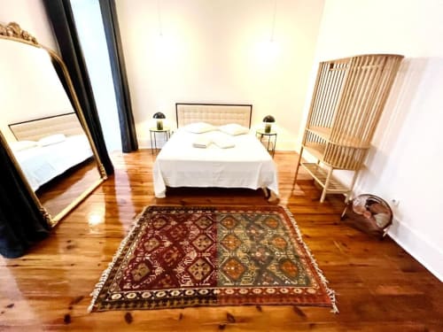 Spacious bedroom at Royal Prince Garden Apartments, Lisboa with wooden floors, ornate rug, white bed, and rattan chair