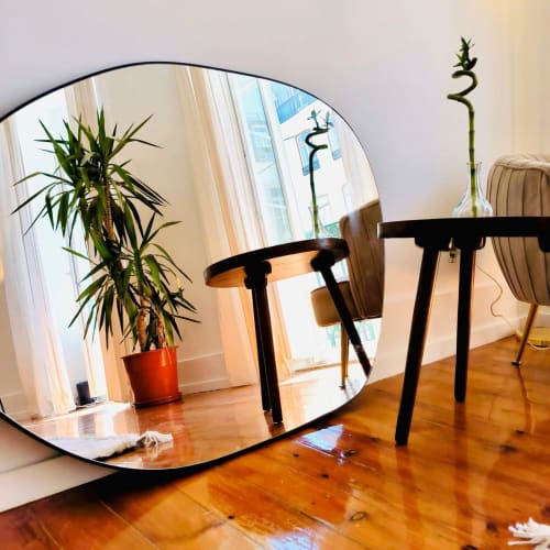 Modern hotel room at Royal Prince Garden Apartments in Lisbon with round mirror, wooden table, potted bamboo plant, and city