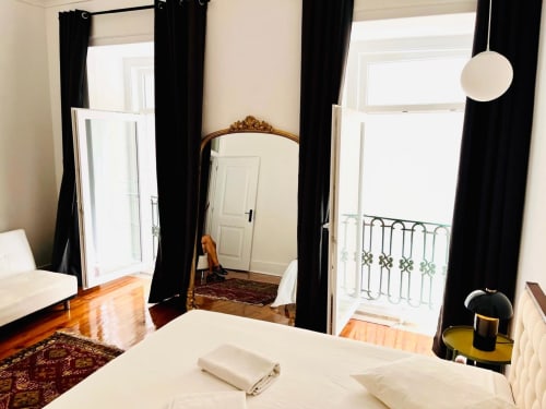 Quarto elegante no Royal Prince Garden Apartments em Lisboa com cama de dossel, espelho ornamentado, cortinas pretas e varanda