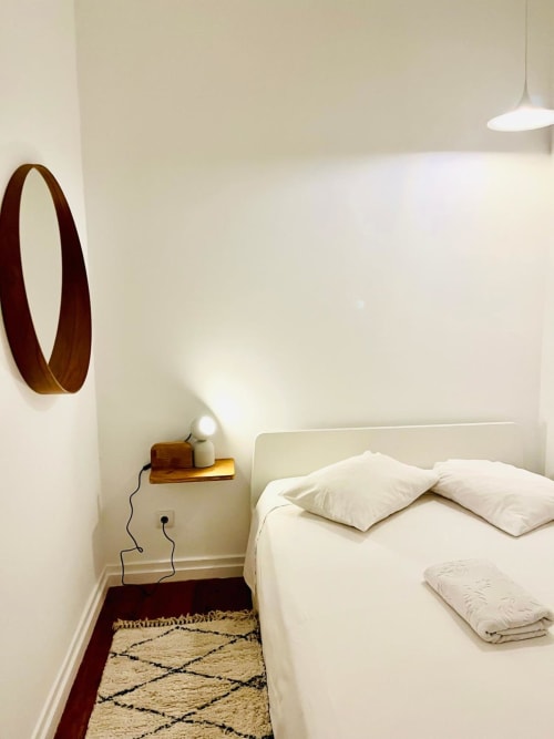 Quarto minimalista no Royal Prince Garden Apartments Lisboa com roupa de cama branca, detalhes em madeira e iluminação pendente