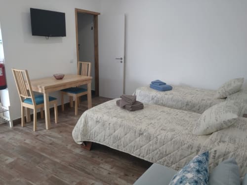 Quarto espaçoso da Casa do Pão com duas camas, mesa de madeira, TV de tela plana e móveis modernos