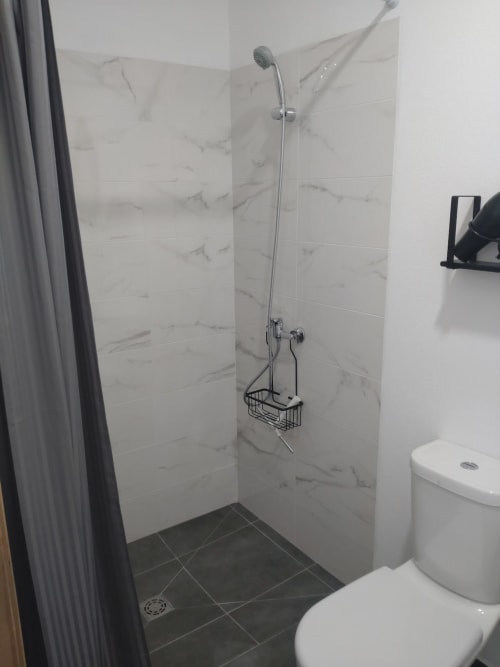 Chuveiro moderno no apartamento Casa do Pão em Campinho com azulejos efeito mármore e chuveirão de chuva