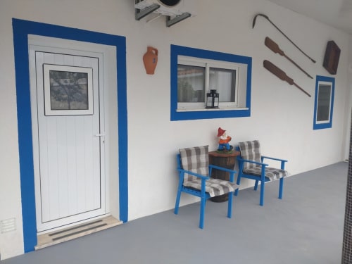 Sala de estar com moldura azul no apartamento Casa do Pão, com cadeiras listradas, janela e porta em Campinho, Portugal