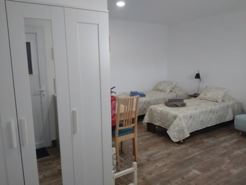 Quarto claro da Casa do Pão com duas camas, móveis de madeira e portas de guarda-roupa brancas em Campinho