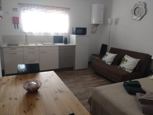 Casa do Pão apartment in Campinho with kitchenette, dining table, brown sofa, and bed in open-plan layout