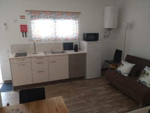 Modern kitchenette with stove, sink, and refrigerator in Casa do Pão 3 apartment in Campinho, Portugal