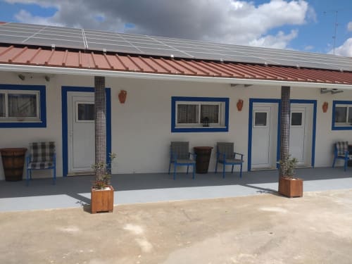 Exterior do apartamento Casa do Pão em Campinho com fachada branca e detalhes em azul, painéis solares e pátio mobiliado