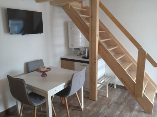 Sala de estar moderna com mesa de refeições, escadas em madeira, kitchenette e TV de ecrã plano na Casa do Pão