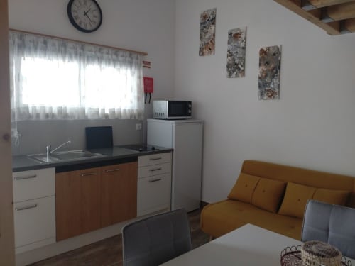Cozinha e área de estar no apartamento Casa do Pão com eletrodomésticos modernos, janela e sofá mostarda