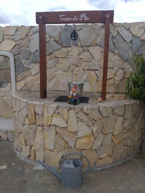 Poço de desejos da Casa do Pão com estrutura de pedra e vista para o jardim em Campinho, Portugal