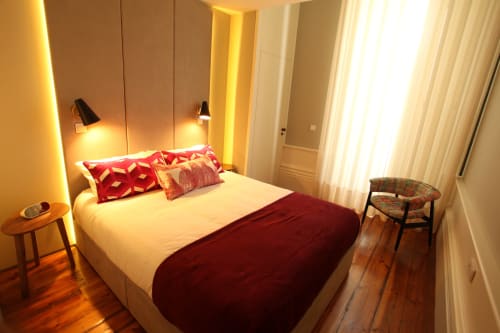 Modern bedroom in New Oporto Apartments Porto with queen bed, red accent pillows, ambient wall lighting, wooden flooring, and