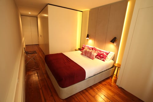 Quarto moderno no New Oporto Apartments Porto com acentos vermelhos, pisos de madeira, iluminação ambiente e vistas para a cidade