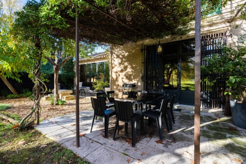 Patio ombragé avec table et chaises noires à Le Mas F, gîte de charme à Saint Rémy de Provence