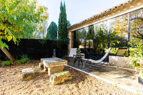 Cour du Mas F avec terrasse en gravier, banc en pierre, transats et extension vitrée contemporaine à Saint-Rémy-de-Provence